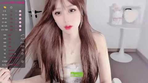 Media: Video of an Asian woman with long brown hair, red lipstick, wearing a strapless top, holding a hairbrush, in a modern, minimalist room with a white stool and a plant.