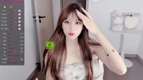 Media: A video of a young East Asian woman with long brown hair, fair skin, and red lipstick, wearing a white top, in a modern, minimalistic room with white walls, a round table, and a door.