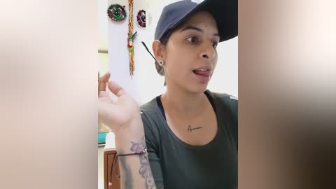 Media: Video of a Latina woman with medium brown skin, short dark hair, and a black cap, holding a cigarette in a dimly lit room, adorned with festive ornaments.