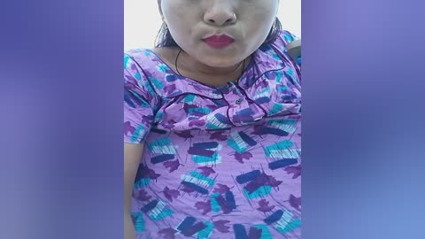 Media: Video of a young Asian woman with short black hair, wearing a purple t-shirt with a graphic design of blue and white cars. She is pouting with red lipstick.