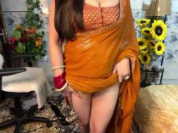 Media: Video of a voluptuous woman with long brown hair, wearing an orange sari with a brown bra, lifting the sari to expose her bare thighs and red bracelets.