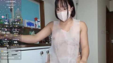 Media: A video shows an East Asian woman with straight black hair and a white mask, wearing a see-through apron, standing in a kitchen with a virtual reality display overlay.