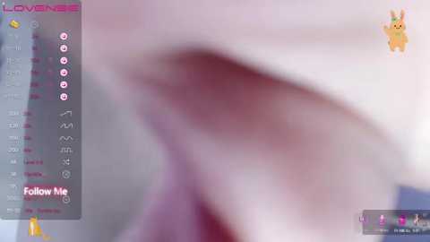 Media: A blurred, out-of-focus image featuring a close-up of a person's face with pink lipstick, possibly on a computer screen with a pink background and a yellow bunny icon.