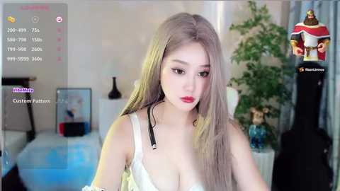 Media: A video of a young Asian woman with long, straight, platinum blonde hair, wearing a white, lacy bra, in a modern, bright room.