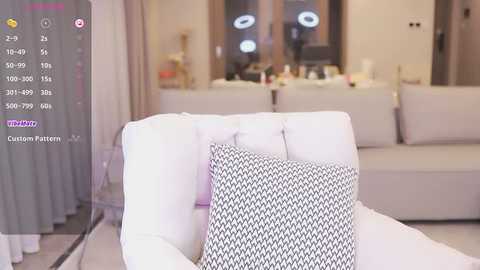 Media: Video of a modern living room with a white couch featuring a black-and-white patterned pillow. Soft, ambient lighting, neutral decor, and a virtual reality interface overlay.