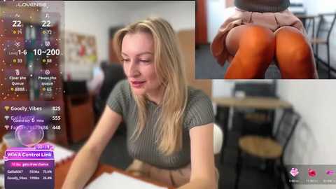 Media: Video of a blonde woman in a gray sweater and tight orange leggings, sitting at a desk in an office.