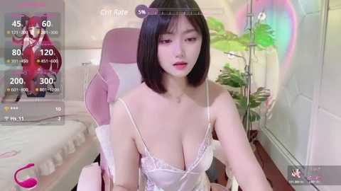 Media: Video of an East Asian woman with short black hair and pale skin, wearing a white lace lingerie set, seated on a pink chair in a brightly lit bedroom with a potted plant.