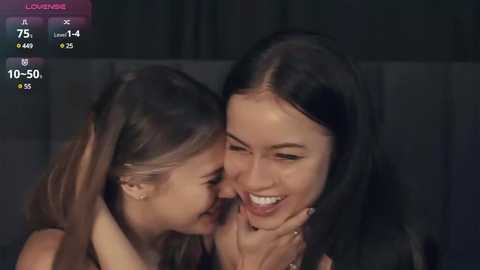 Media: Video of two young women, one with long brown hair, one with long black hair, smiling and embracing in a dimly lit room, with a \"Louise\" screen overlay.