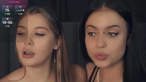 Media: Video of two young women with fair skin, long hair, and different eye makeup, kissing passionately; background is dark and indistinct.