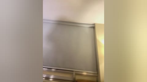 Media: A blurry video of a modern bathroom with a beige wall, a metal shower rail, and a partially visible shower curtain. The lighting is soft, creating a muted ambiance.