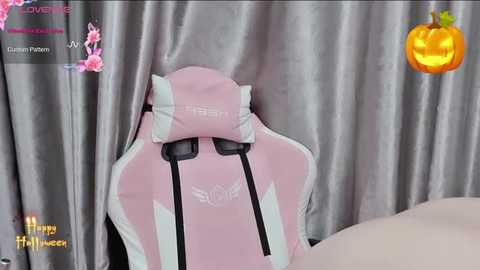 Media: Video of a pink gaming chair with black accents, set against a gray curtain backdrop, with a pumpkin icon and \"Happy Halloween\" text overlay.