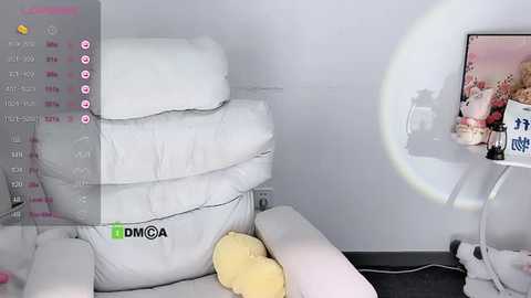 Media: Video of a minimalist living room with a white leather recliner, yellow pillow, white walls, and a white table with stuffed toys and a framed photo.