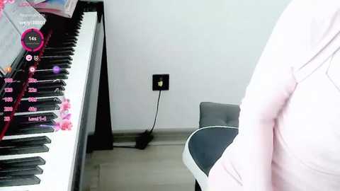 Media: A video of a modern, minimalist room with a white wall, a black keyboard, and a person in a pink shirt.