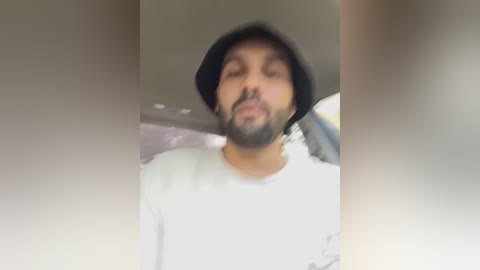 Media: A blurry, low-quality video of a bearded man in a white t-shirt and black beanie, making a funny face, possibly in a car.