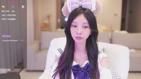 Media: Video of an Asian woman in a sailor uniform with long black hair and a bunny headband, sitting indoors. Background shows a beige couch.