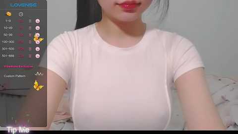 Media: Video of an East Asian woman with long black hair, wearing a tight white T-shirt, smiling with red lipstick, in a bedroom. Live streaming interface on the left shows viewers and chat.