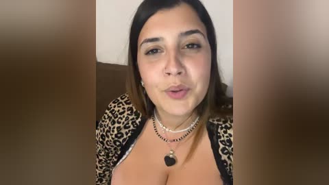 Media: A video of a Latina woman with medium skin tone and dark brown hair, wearing a leopard print top, making a kissing face.