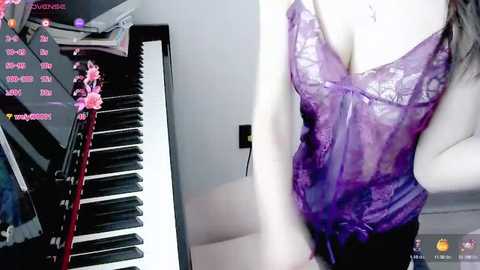 Media: Video of a woman in a purple lace bra and black skirt, playing a digital piano, with a live stream overlay of virtual pink flowers.