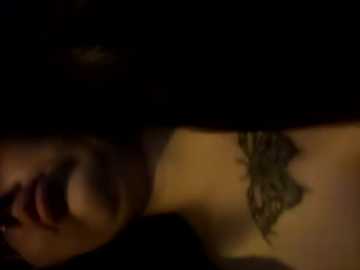 Media: A dimly-lit video shows a close-up of a woman's face with a black choker, partially visible tattoo on her right shoulder, and dark makeup.