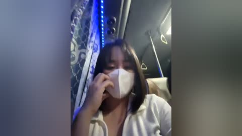 Media: A video of a person wearing a white face mask, sitting in a dimly-lit car with blue LED strip lights and intricate patterns on the seats.