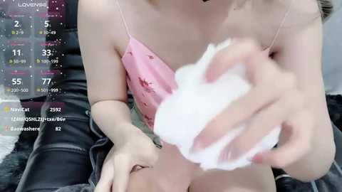 Media: Video of a fair-skinned woman with a slender physique, wearing a pink camisole and black pants, washing her face with a white cloth. Background shows a calendar and social media icons.