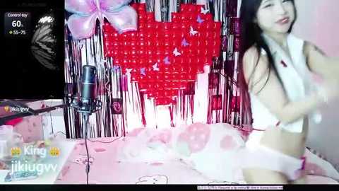 Media: A video of a young Asian woman with long black hair, wearing white lingerie, dancing in a pink-themed room with heart-shaped decorations.