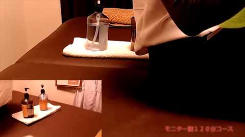 Media: Video of a Japanese-style room with a dark wooden table, white towel, and bottle of clear liquid; reflection shows a partially visible person in a white shirt and black pants.