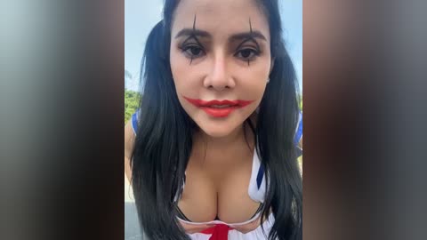 Media: Video of a woman with long black hair, wearing a revealing costume with red lipstick, in a public setting with blurred background.