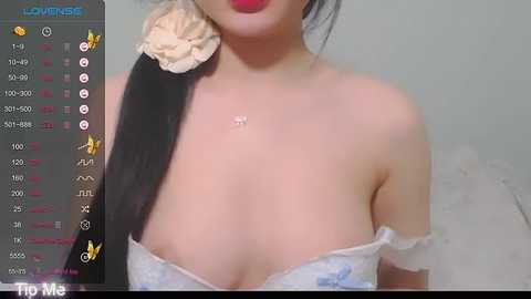 Media: Video of an East Asian woman with pale skin and black hair in a bun, wearing a strapless, white floral-patterned dress, revealing cleavage. Background shows a recording screen with live stream info.