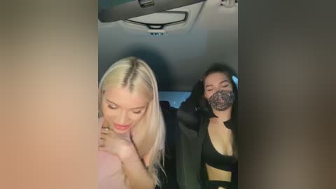 Media: Video of two women in a car: blonde woman with light skin, wearing a black mask, touching a dark-skinned woman's face.