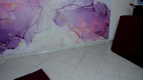 Media: A video of a room with a vibrant, abstract, purple and pink marble-like wall mural. The floor is white tile with a maroon rug. A dark brown dresser stands against the wall, partially visible.