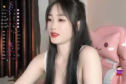 Media: Video of a young Asian woman with long black hair, fair skin, and red lipstick, wearing a white tank top, seated in a pink gaming chair.