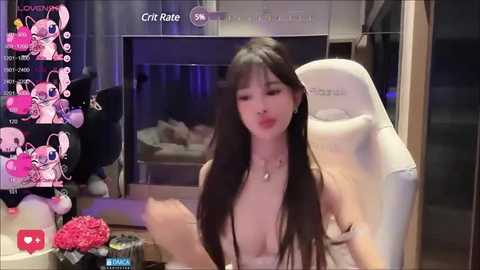 Media: A video of an Asian woman with long black hair, wearing a revealing, low-cut top, sitting in a white gaming chair, surrounded by gaming equipment and plush toys.