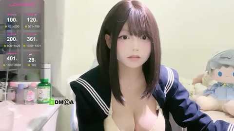 Media: Video of a young East Asian woman with straight, shoulder-length black hair, wearing a revealing navy blue sailor school uniform with a low-cut neckline, in a bedroom with stuffed toys.