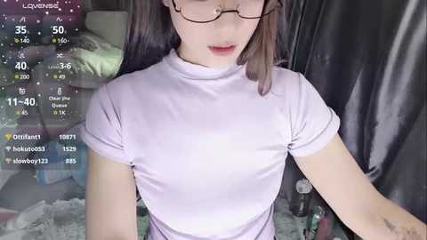 Media: A video of a young Asian woman with glasses and a small breast size, wearing a tight, light pink top, taken indoors with a live streaming overlay showing chat messages.