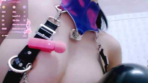 Media: Video of a woman in a bondage collar and pink gag, wearing a blue and purple hood, large breasts partially exposed, with a \"LIVE\" overlay.