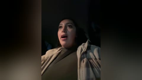 Media: Video of a distraught, middle-aged woman with dark hair, wearing a beige robe, mouth agape in shock, dimly lit background, suggesting a dramatic scene.