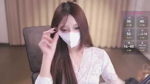 Media: Video of an East Asian woman with long brown hair, wearing a white lace dress and face mask, adjusting her hair in a living room with beige curtains. Weather app overlay shows 16\u00b0C, 40% humidity, and 16 mph wind.