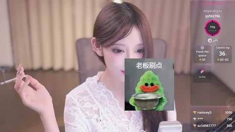 Media: A video of an Asian woman with light skin and straight brown hair, wearing a white lace blouse, smoking a cigarette in a dimly lit room with beige curtains. Superimposed over the image is a green frog emoji with a bowl of noodles.