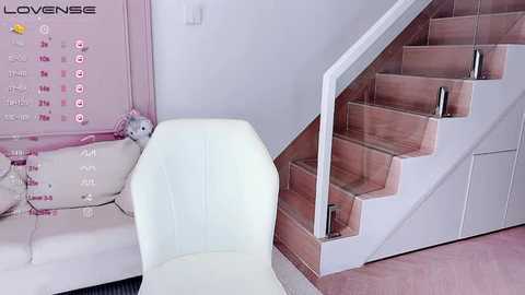 Media: A video of a modern, minimalist living room with a white leather chair, pink wall calendar, and wooden staircase with metal railings.