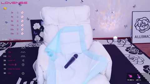 Media: Video of a VR scene showing a white recliner chair with a blue dildo, surrounded by floral-patterned decor and a calendar, in a modern, minimalist room.