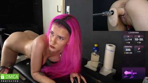 Media: Video: A nude, fair-skinned woman with bright pink hair, medium breasts, and tattoos, performing oral sex on a man. Background shows medical equipment.