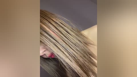 Media: Video of a woman with long, straight, light brown hair partially covering her face, featuring a close-up view highlighting the hair's texture and color.