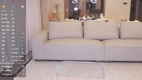 Media: Video of a modern, minimalist living room with a beige leather sofa, white curtains, and a glass coffee table, featuring a smartphone screen displaying a weather app.