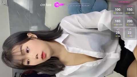 Media: Video of an Asian woman with shoulder-length black hair, wearing a white button-down shirt, lying on a couch in a modern room.