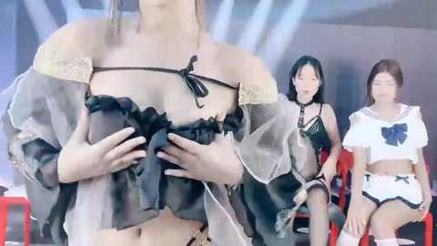 Media: Video of three Asian women in provocative sailor maid costumes, one covering her breasts, another smiling, and a third in the background, all in a modern, brightly lit room.