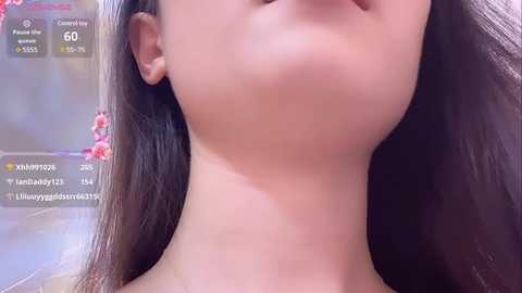 Media: Video of a young Asian woman with smooth, fair skin, long dark hair, and a slender neck. Background shows social media app interface, displaying likes and comments.