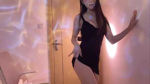 Media: A video of an East Asian woman in a black mini dress, standing provocatively against a glowing wall. She has long black hair, fair skin, and a slim figure.