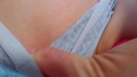 Media: A close-up video of a person's hand gently pulling down light blue panties, revealing a light-skinned, slightly hairy groin area.