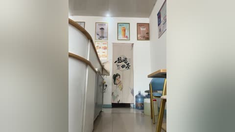 Media: Video of a narrow, white-walled hallway with wooden railings, featuring Japanese posters and a mural with a woman. The floor is tiled, and a water cooler is placed near the end.